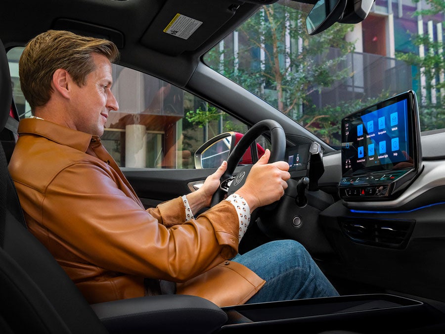 Interior view on a man in the driver seat an ID.4 SUV with his attention focused on the center console display at startup.